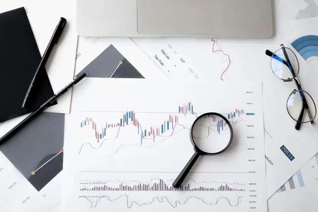 Flat lay of stock market analysis documents with magnifying glass, pens, and glasses. Sådan sammenligner du branchekategorier på krav og dokumentation