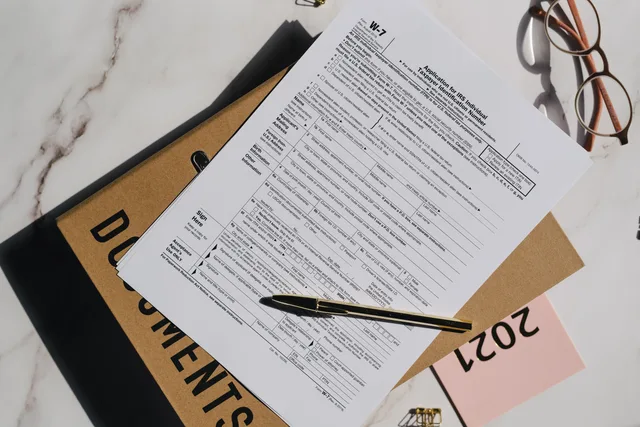 Top view of a tax form with a pen and eyeglasses on a marble surface, perfect for finance themes. Sådan tjekker du CVR-oplysninger i en virksomhedsprofil